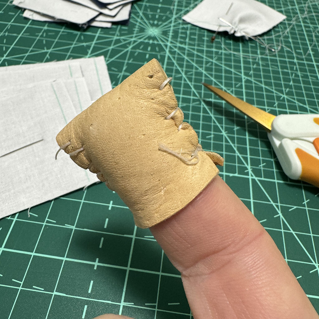 A doeskin homemade thimble on the tip of my index finger.