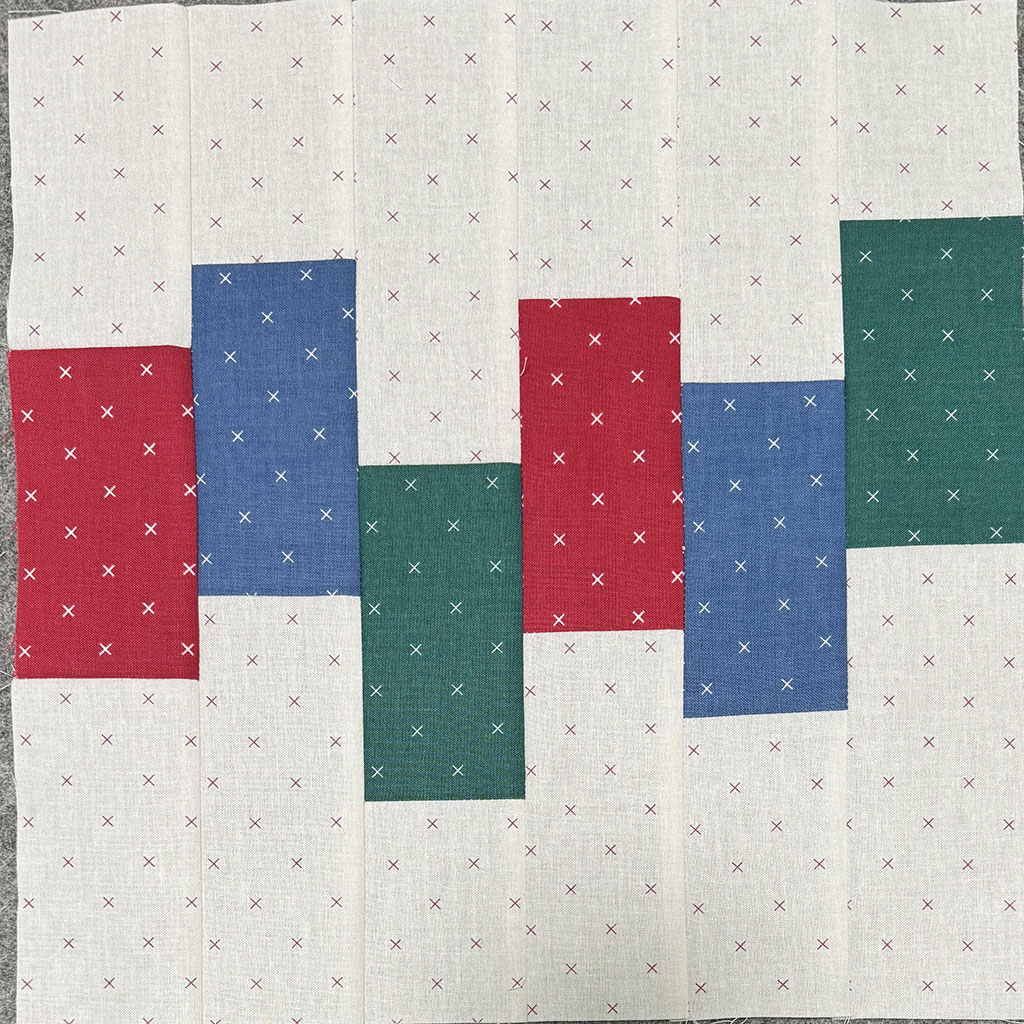 6 strips side by side. Each strip has light fabric at top and bottom, and a colored area in the center. The colored areas are offset and don't match.