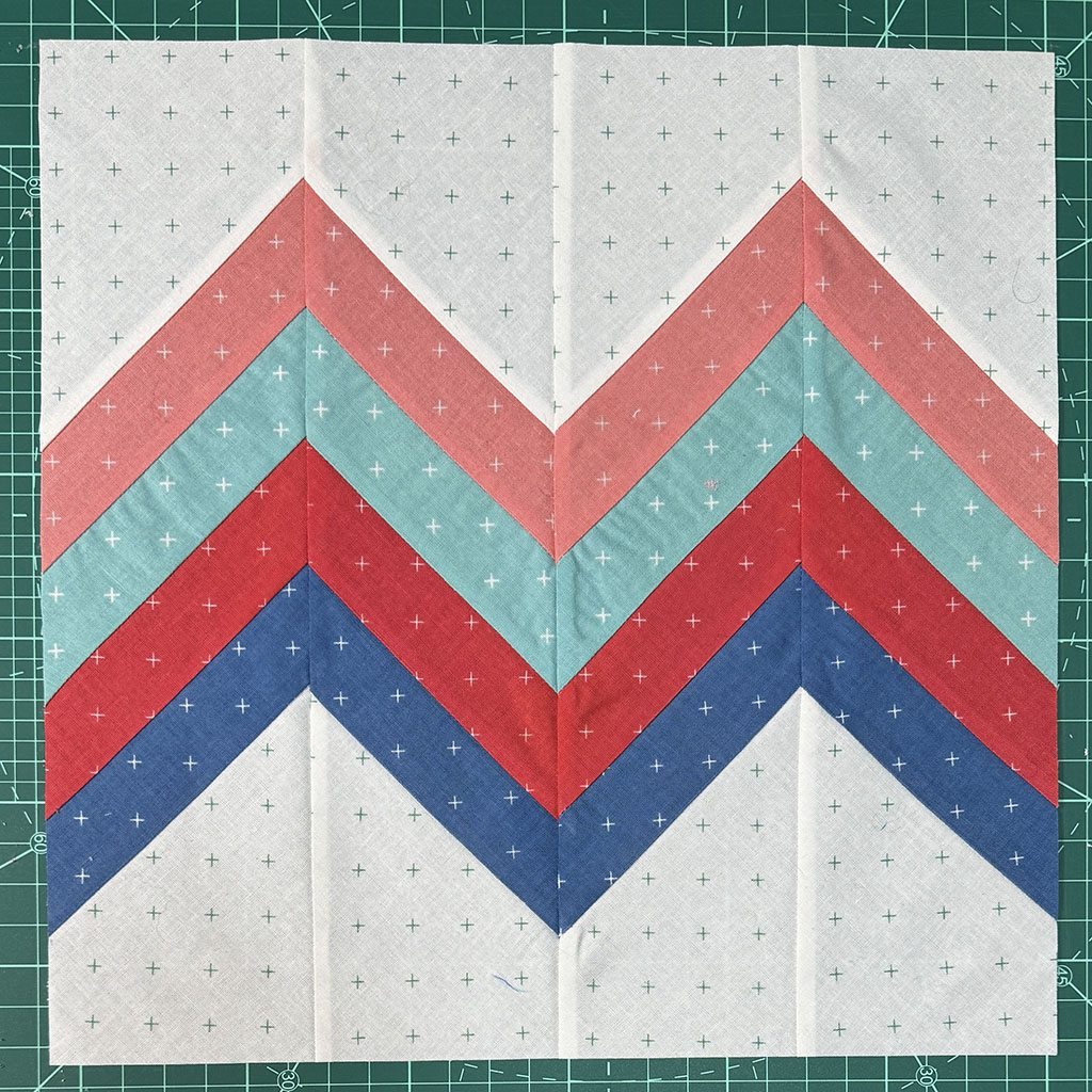 4 narrow color strips forming chevrons with 2 peaks on one side of the block and 1 peak on the other