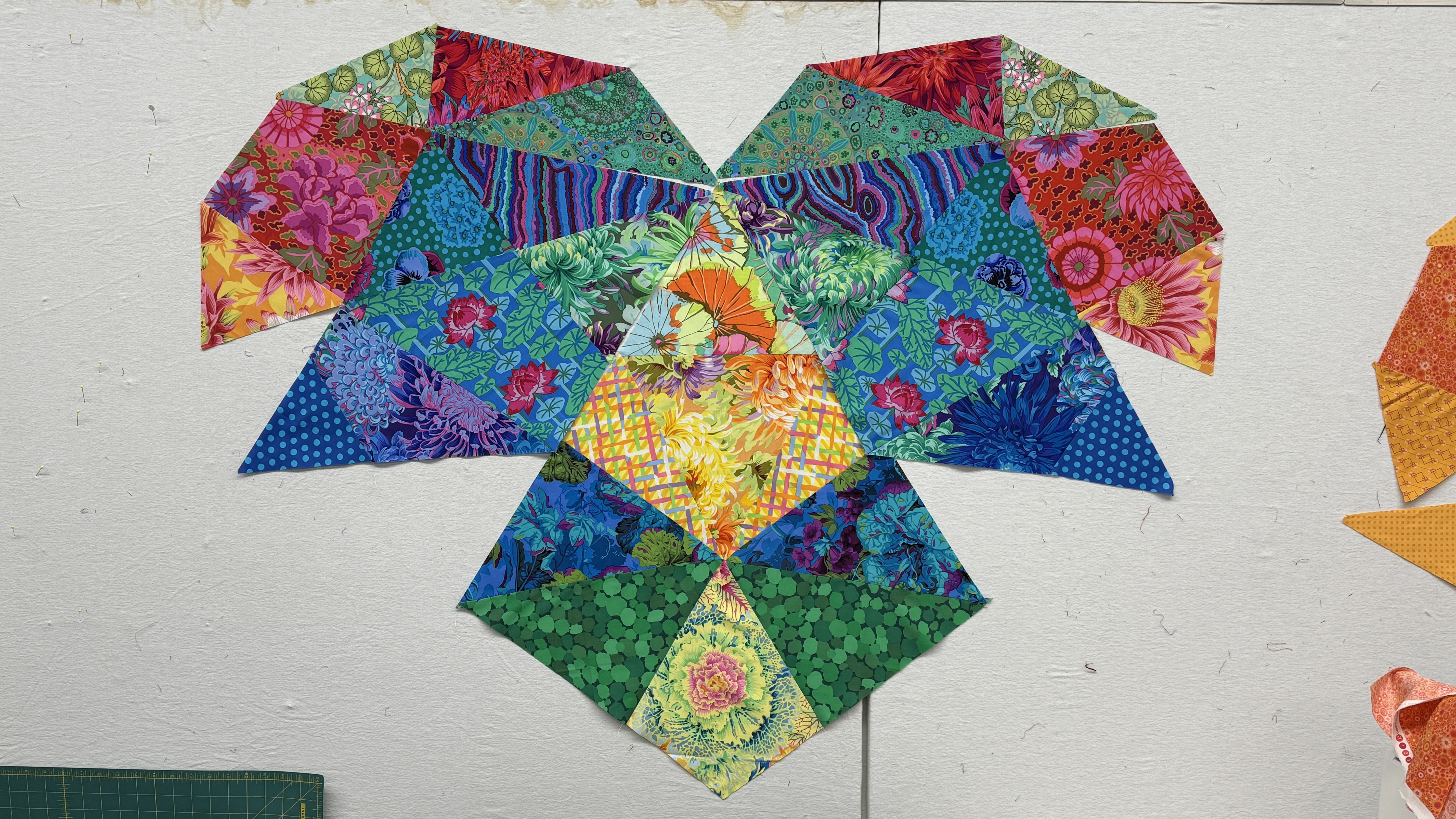 Several blocks of colorful fabrics up on a design wall.