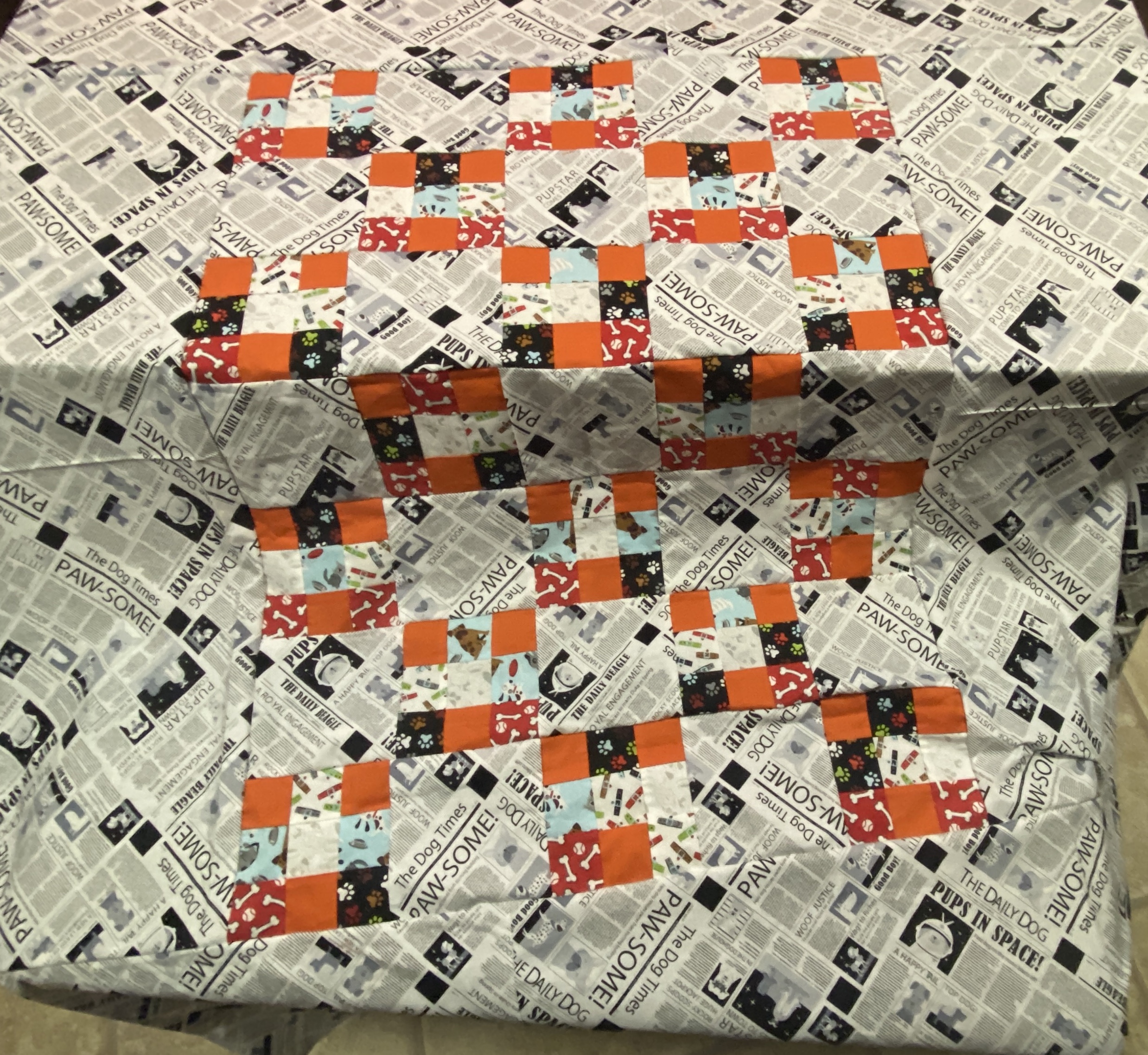The pieced back of a quilt. There's a black and white outter edge, with a large rectangle in the center made of smaller squares in oranges and blacks and reds.