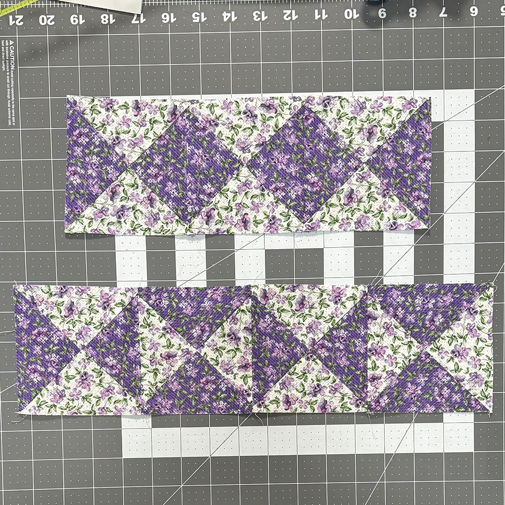 Two blocks made of quarter square triangles. One block has three squares where the dark fabric triangles meet. The other has 4 squares where the dark and light triangle meet. The fabrics are a dark and a light variation of lavender flower print.